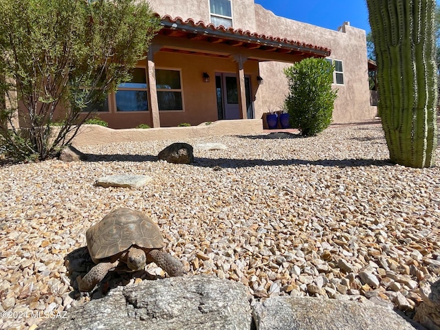 rear view of property with stucco siding and a tile roof