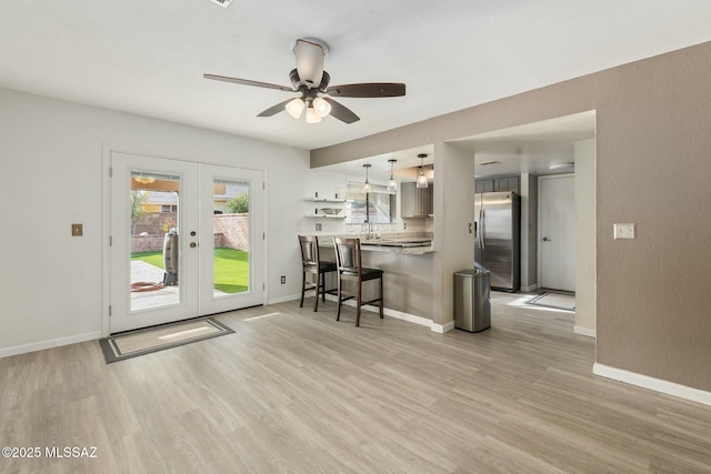 kitchen with stainless steel fridge, a breakfast bar area, kitchen peninsula, decorative light fixtures, and french doors