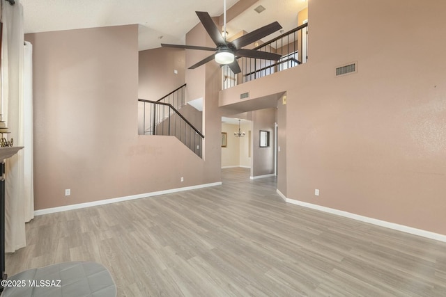 unfurnished living room featuring ceiling fan with notable chandelier and light hardwood / wood-style flooring