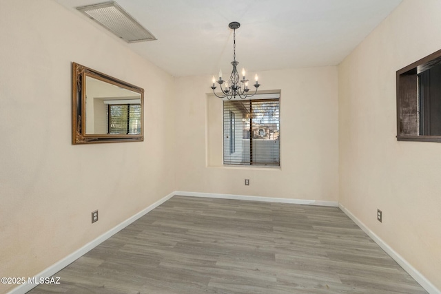 unfurnished room with hardwood / wood-style floors and an inviting chandelier