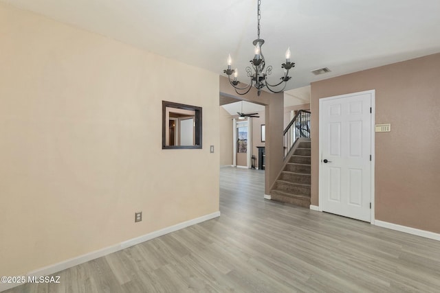 unfurnished room featuring a notable chandelier and light hardwood / wood-style flooring