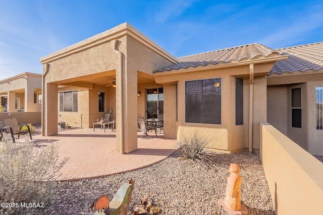 back of property with ceiling fan and a patio