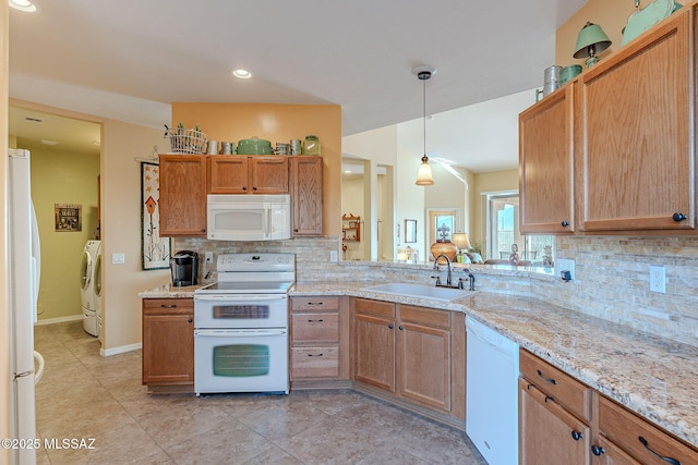 kitchen featuring sink, white appliances, tasteful backsplash, separate washer and dryer, and decorative light fixtures