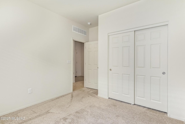 unfurnished bedroom with light carpet and a closet