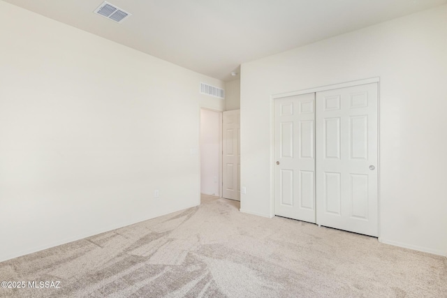 unfurnished bedroom featuring light carpet and a closet