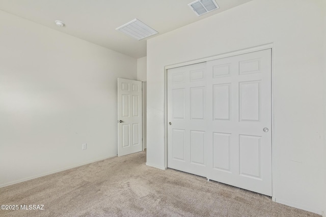 unfurnished bedroom with light colored carpet and a closet