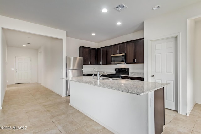 kitchen featuring sink, stainless steel appliances, light stone countertops, dark brown cabinets, and a center island with sink