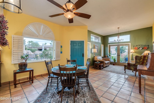 dining room with tile patterned flooring, ceiling fan with notable chandelier, and french doors