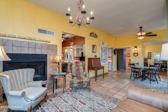 living room with a textured ceiling, a tile fireplace, ceiling fan, and light tile patterned flooring