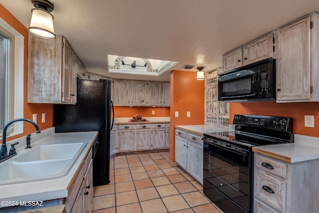 kitchen with sink, a textured ceiling, light tile patterned floors, light brown cabinets, and black appliances