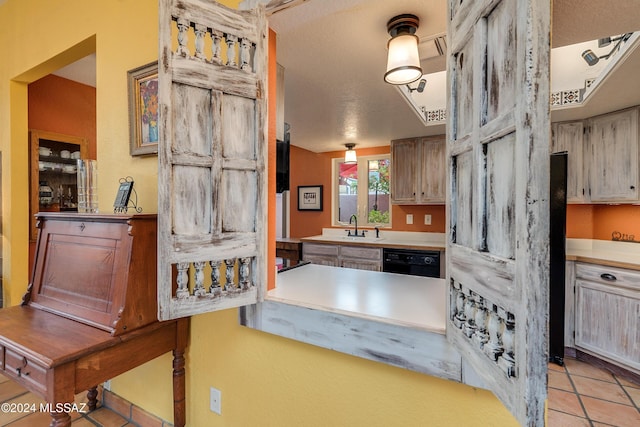 kitchen with light tile patterned flooring, black dishwasher, and sink