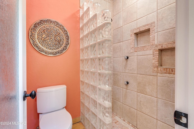 bathroom with tiled shower and toilet