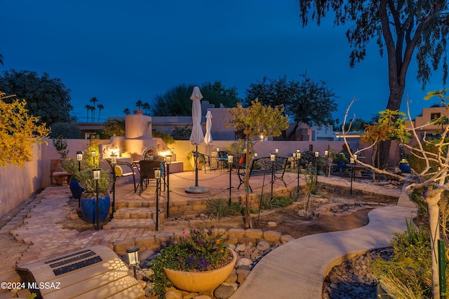 patio at twilight featuring an outdoor fireplace