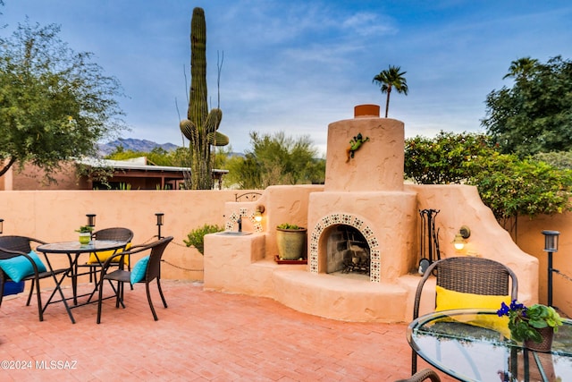 view of patio featuring an outdoor fireplace and a mountain view