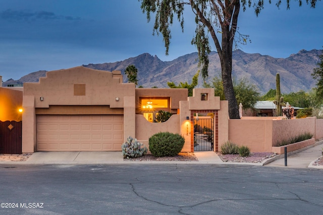 pueblo-style house with a garage and a mountain view