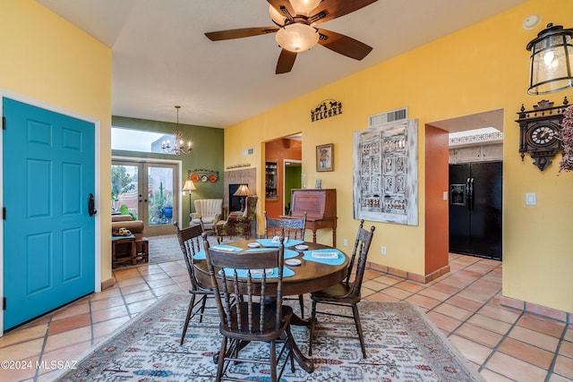 tiled dining area with ceiling fan with notable chandelier and french doors