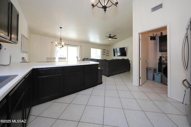 kitchen with washer / clothes dryer, light tile patterned floors, decorative light fixtures, vaulted ceiling, and ceiling fan with notable chandelier