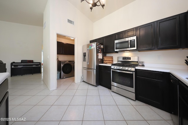 kitchen with a notable chandelier, light tile patterned floors, high vaulted ceiling, separate washer and dryer, and stainless steel appliances