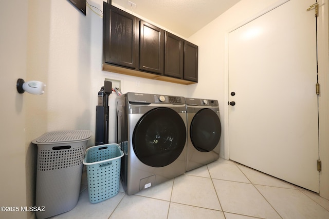 laundry room featuring cabinets, washing machine and dryer, and light tile patterned floors