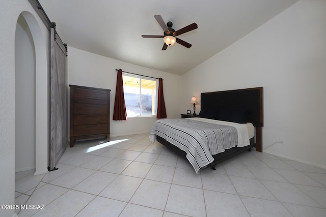 bedroom with ceiling fan, light tile patterned flooring, a barn door, and vaulted ceiling