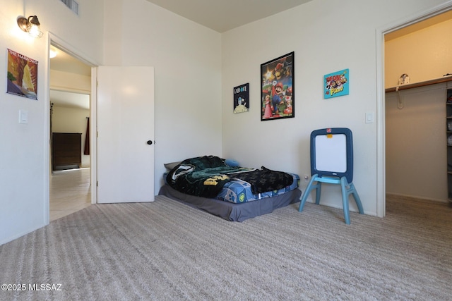 bedroom with a closet, a walk in closet, and light carpet