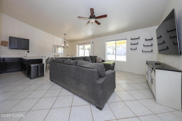 living room with ceiling fan with notable chandelier, light tile patterned flooring, and vaulted ceiling