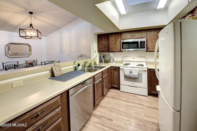 kitchen featuring sink, hanging light fixtures, stainless steel appliances, light hardwood / wood-style floors, and a chandelier