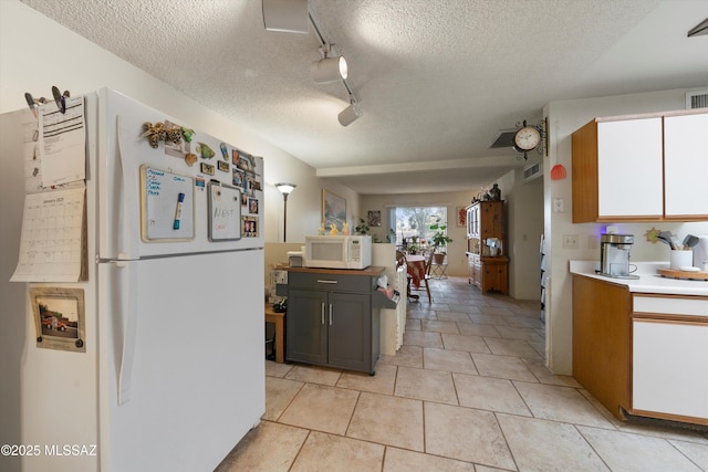 kitchen with light tile patterned floors, white appliances, rail lighting, and a textured ceiling