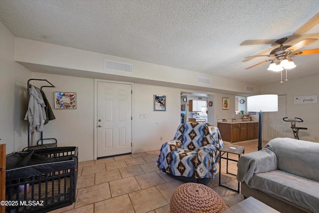 living room featuring ceiling fan, light tile patterned floors, and a textured ceiling