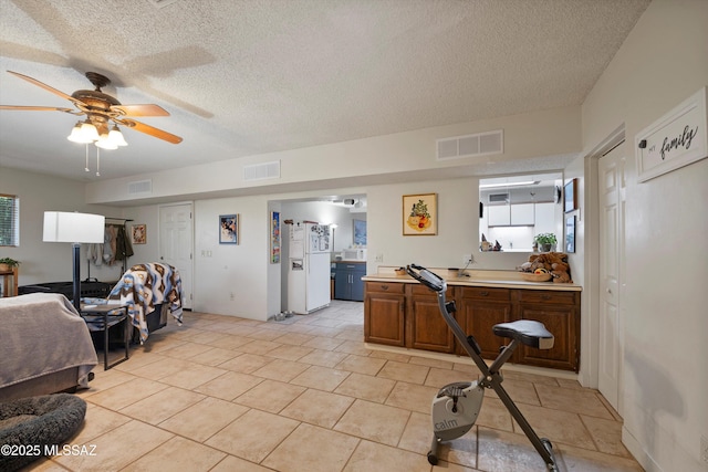 interior space featuring a textured ceiling, a wealth of natural light, ceiling fan, and white refrigerator