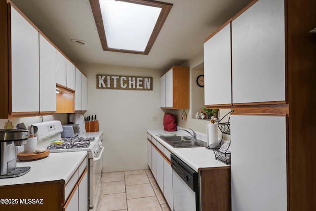 kitchen with sink, white appliances, a skylight, white cabinets, and light tile patterned flooring