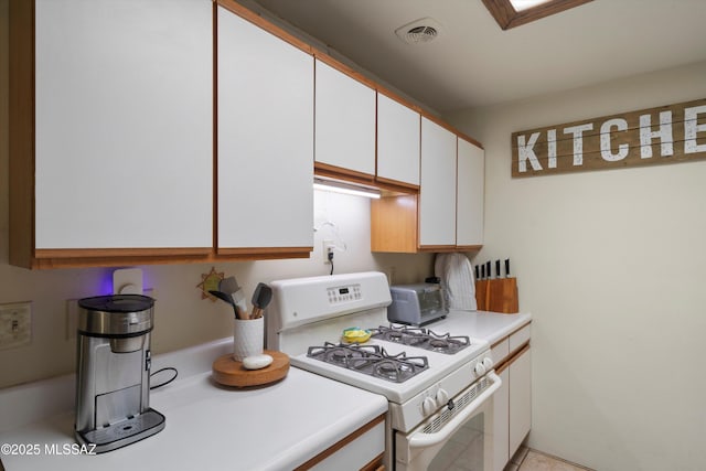 kitchen featuring white range with gas cooktop and white cabinetry