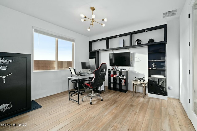 office with light hardwood / wood-style floors and an inviting chandelier