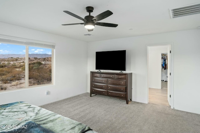 bedroom featuring light carpet, a closet, a spacious closet, and ceiling fan