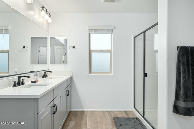 bathroom with a shower with shower door, hardwood / wood-style floors, and vanity