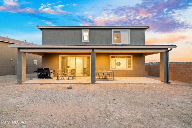 back house at dusk featuring a patio