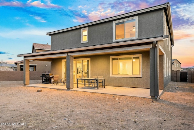 back house at dusk featuring a patio