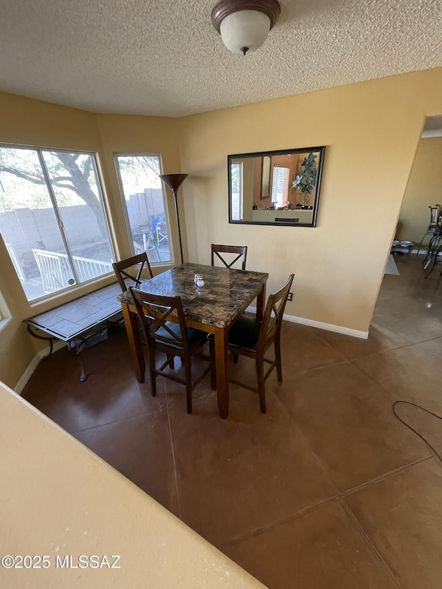 dining space featuring a textured ceiling and dark tile patterned floors