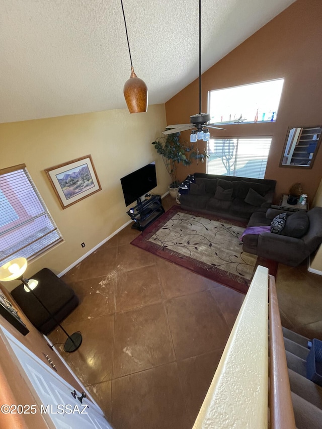 living room featuring dark tile patterned flooring, a textured ceiling, ceiling fan, and vaulted ceiling