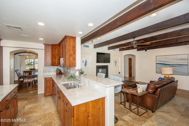 living room featuring dark wood-type flooring, a fireplace, beamed ceiling, and ornate columns