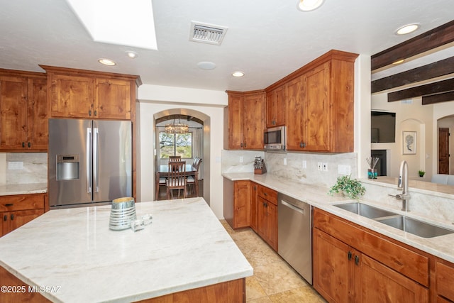 kitchen with arched walkways, appliances with stainless steel finishes, a sink, and visible vents