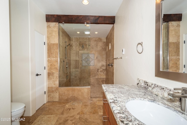 full bath with vanity, a tile shower, and toilet