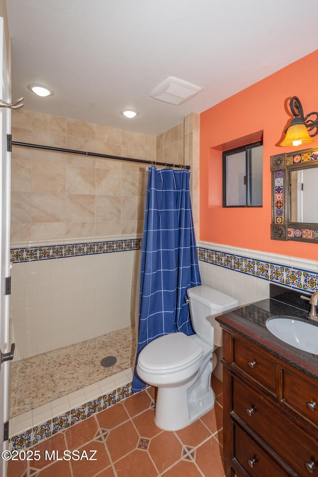 bathroom featuring a wainscoted wall, tiled shower, tile walls, and vanity