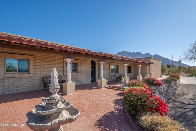 back of property featuring a mountain view and a patio