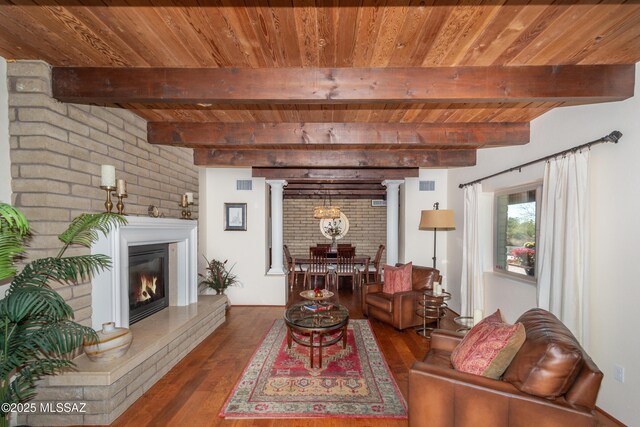 kitchen with light tile patterned floors, white cabinetry, stove, beam ceiling, and brick wall