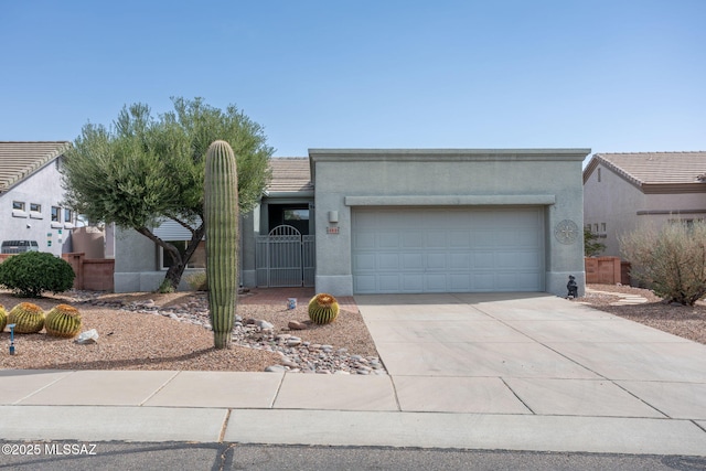 view of front of property with concrete driveway, an attached garage, a gate, fence, and stucco siding