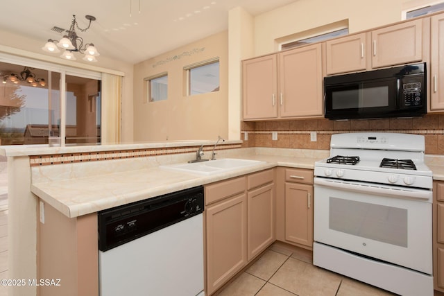 kitchen with white appliances, decorative backsplash, a peninsula, light countertops, and a sink