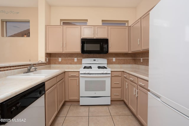 kitchen with white appliances, tasteful backsplash, light countertops, and a sink