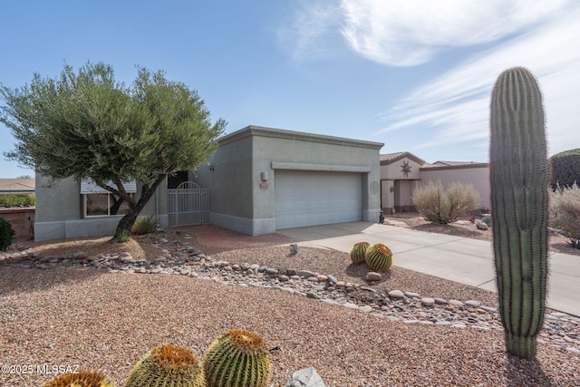 view of front facade with a garage, a gate, concrete driveway, and stucco siding