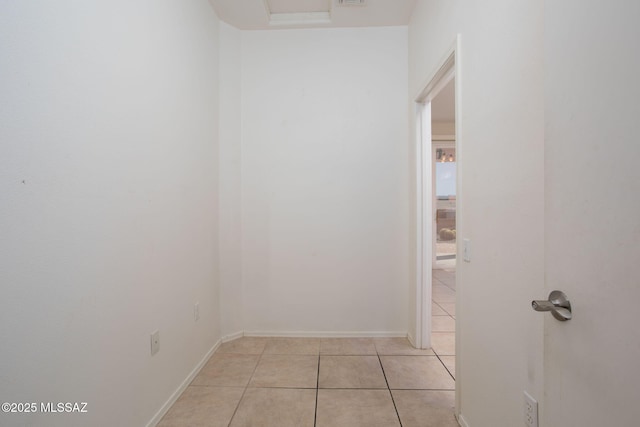 corridor with baseboards and light tile patterned flooring